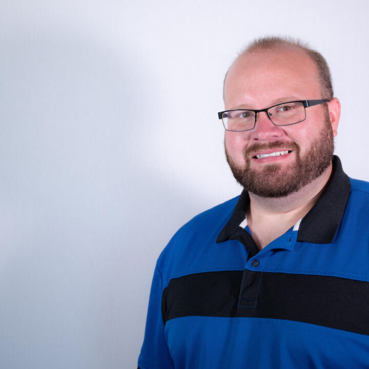 Jordan-Oien-Featured-Image-Blog-Post Headshot of man with glasses and blue and black hair in studio lighting
