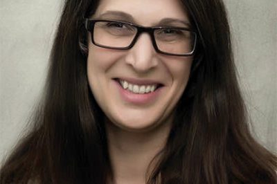 Shoulder-up shot of a woman with long brown hair and glasses