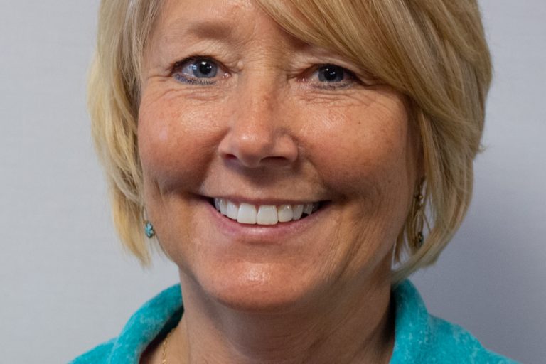 Blonde woman headshot with blue shirt in studio lighting
