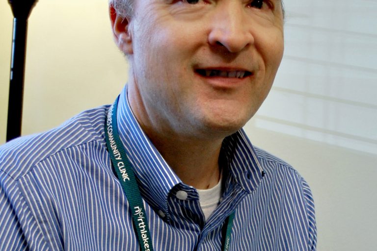 Man smiling with brown hair and striped long sleeve shirt