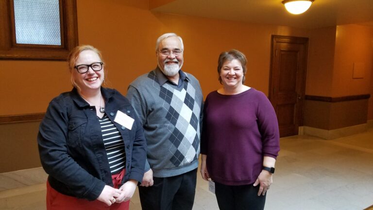 Three staff members smiling inside the Wisconsin State Capitol building