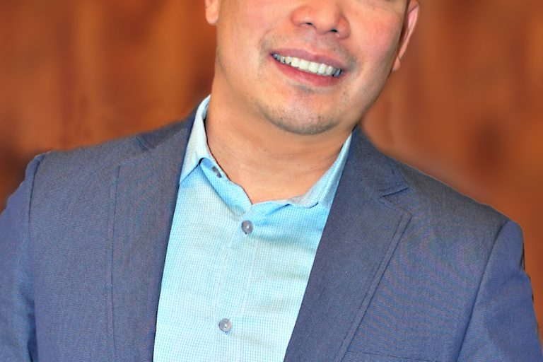 Male smiling and wearing a blue dress jacket