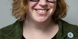 Lori_web Woman smiling with short blonde hair and black glasses