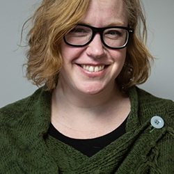 Lori_web Woman smiling with short blonde hair and black glasses