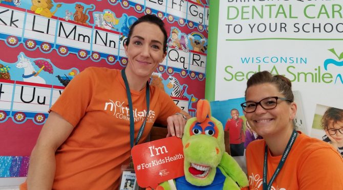 Two women sitting either side of a puppet and smiling