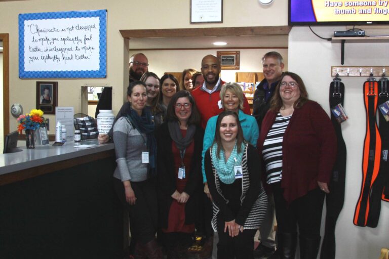 Staff members smiling with Mandela Barnes by front desk in Park Falls