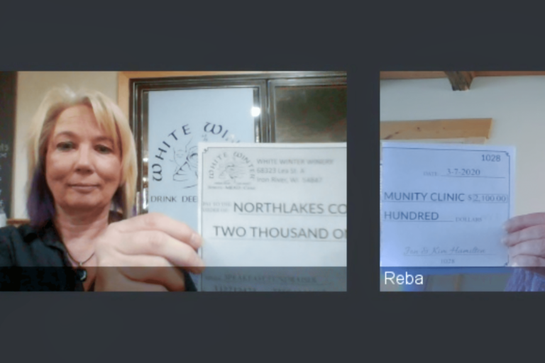 Two women on online meeting holding up a check