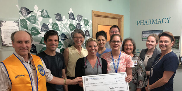 Staff members holding a check and smiling