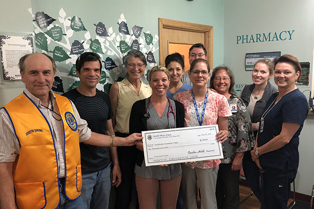 Staff members holding a check and smiling