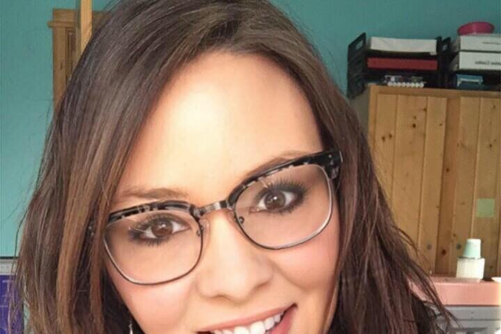 Woman smiling with long brown hair and glasses