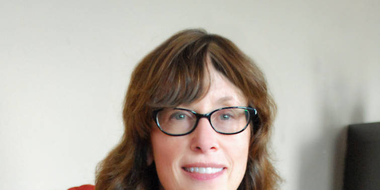 Woman with brown hair and bangs posed with white and black dress and black cardiagan