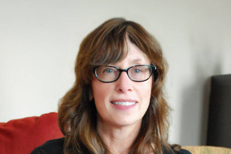 Woman with brown hair and bangs posed with white and black dress and black cardiagan