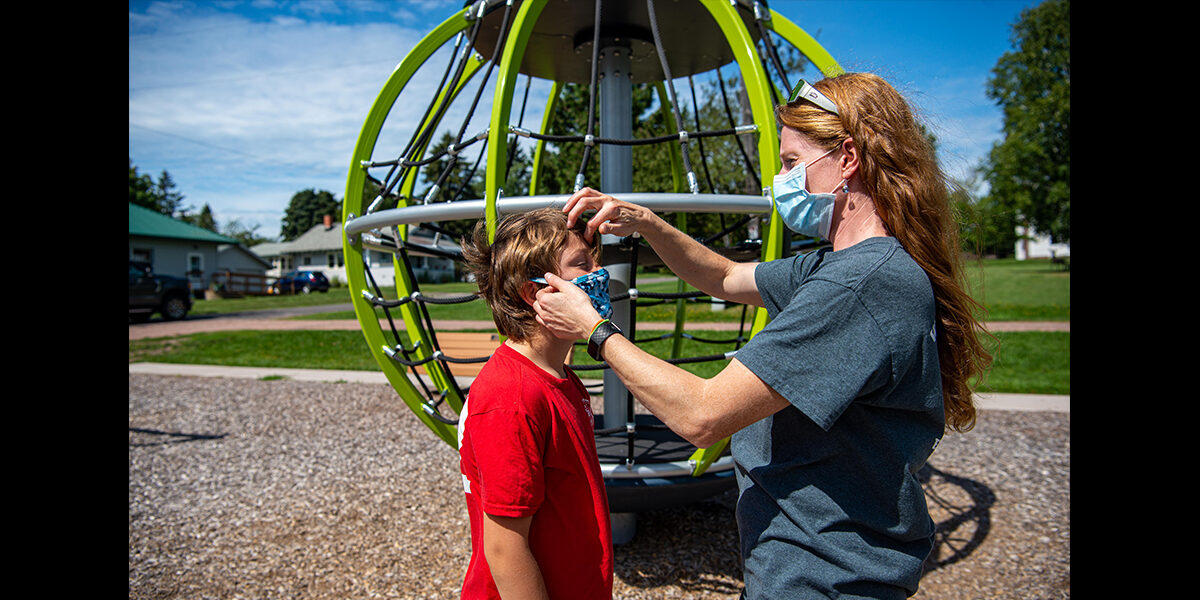 Woman with mask on adjusting her son's mask