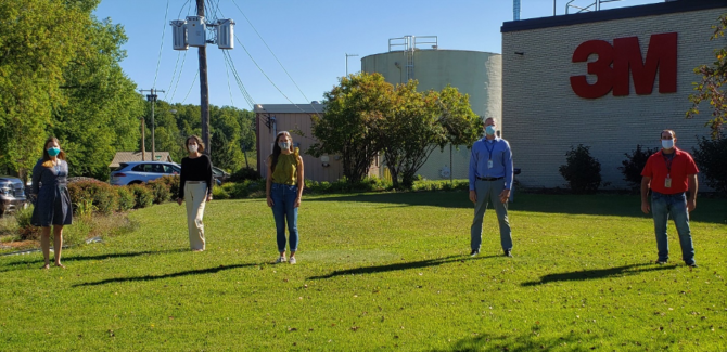 Picture1 Staff members standing outside and wearing face masks, standing far apart from one another