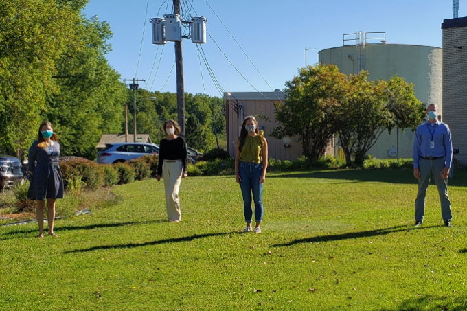 Staff members standing outside and wearing face masks, standing far apart from one another