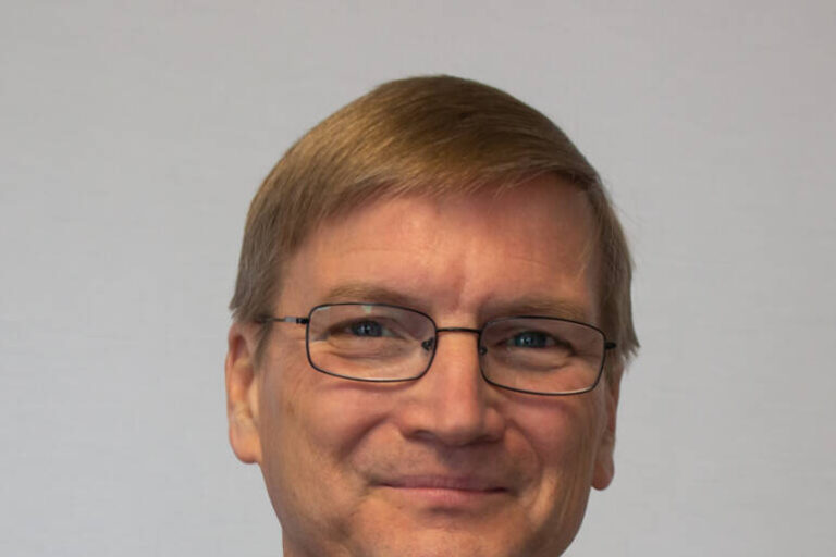 Headshot of man with glass and turtleneck sweater