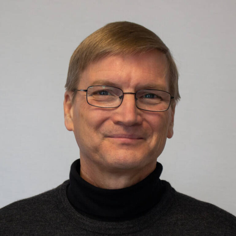 Headshot of man with glass and turtleneck sweater