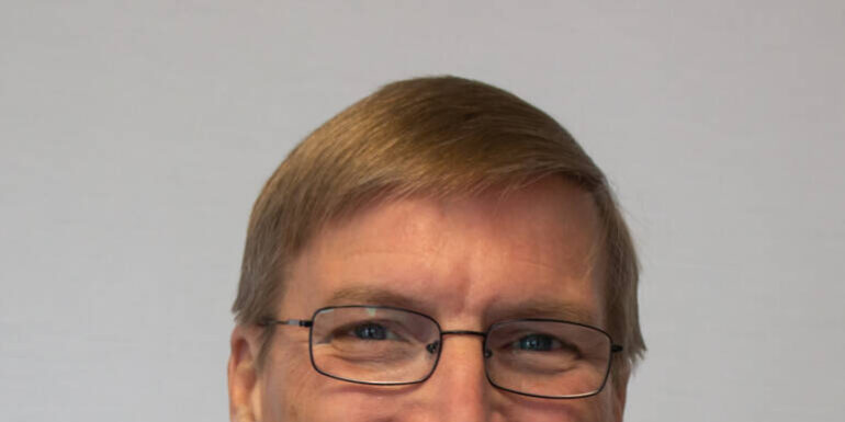 Headshot of man with glass and turtleneck sweater