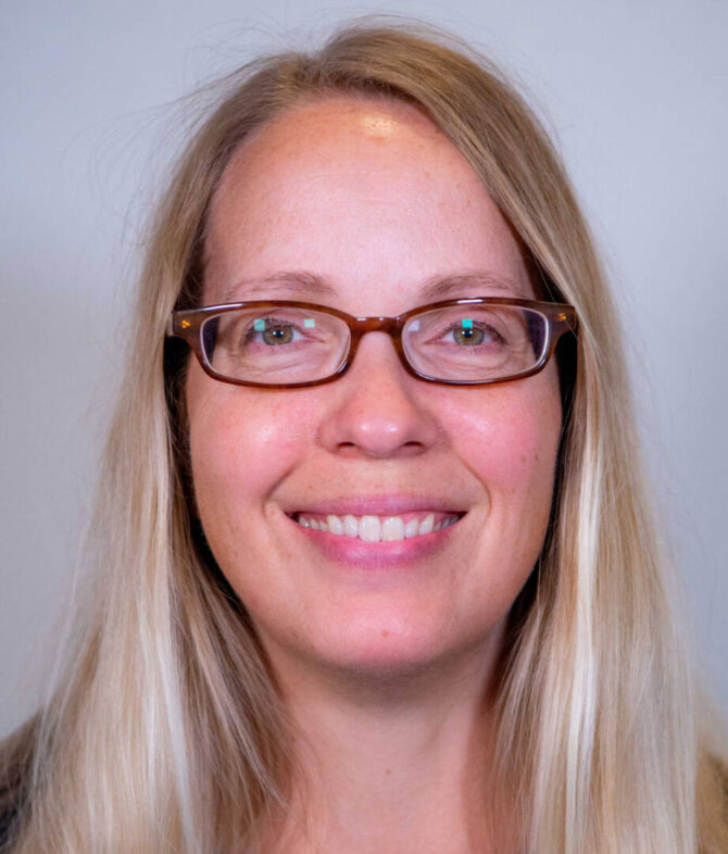 Close up headshot of woman with straight blond hair and glasses