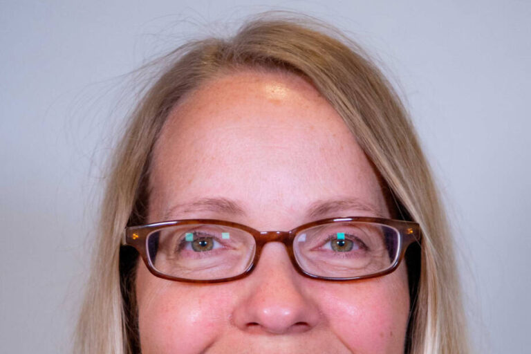 Close up headshot of woman with straight blond hair and glasses