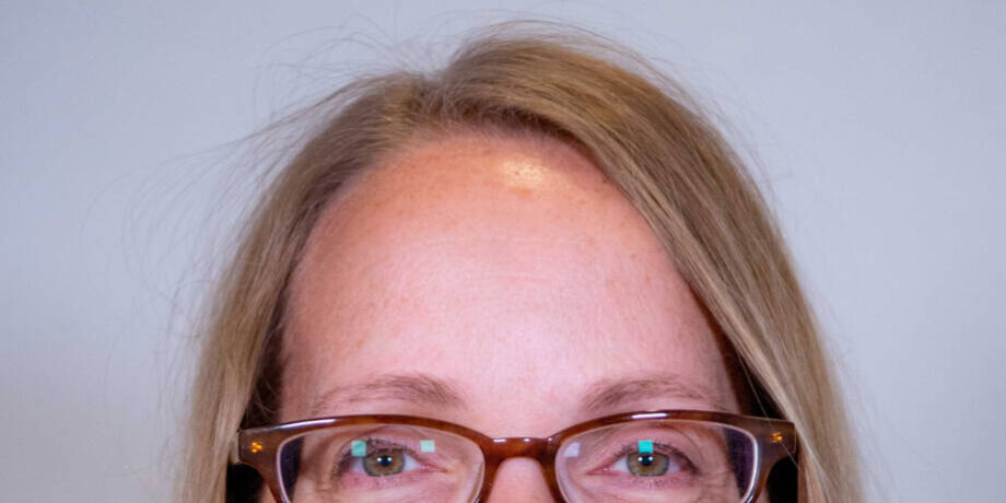 Close up headshot of woman with straight blond hair and glasses
