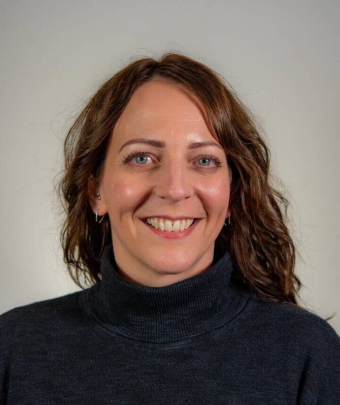 Woman with wavy brown hair and turtleneck sweater