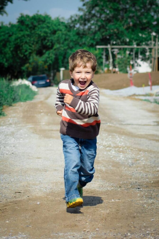 pexels-luna-lovegood-1104007 Young boy smiling and running down dirt road