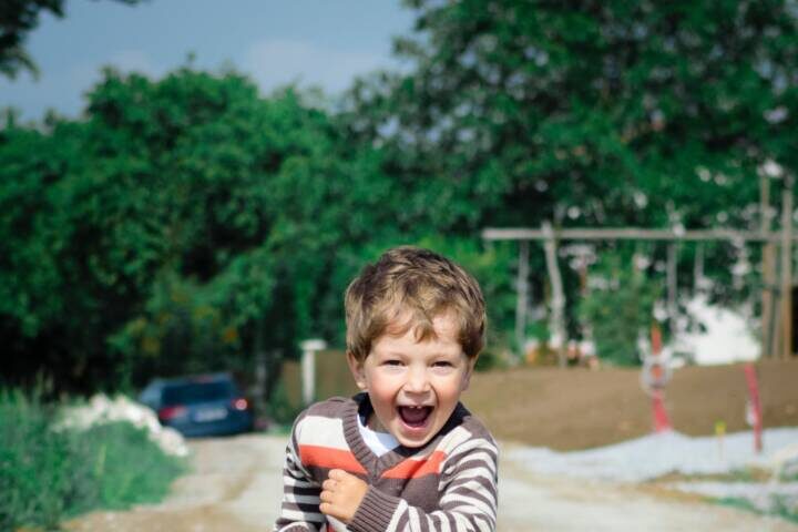 Young boy smiling and running down dirt road