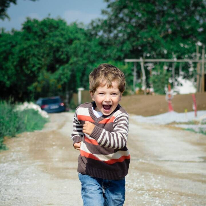 pexels-luna-lovegood-1104007 Young boy smiling and running down dirt road