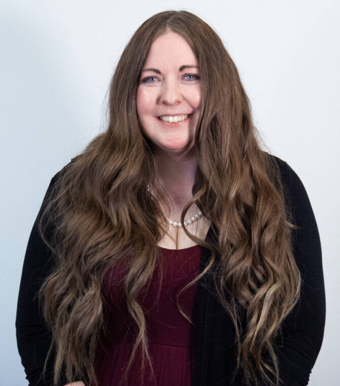 Woman with tailbone length brown hair and black cardigan