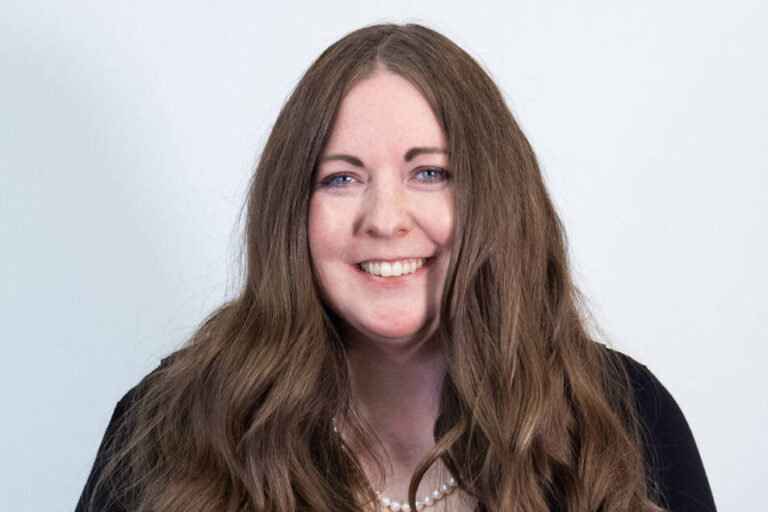 Woman with tailbone length brown hair and black cardigan