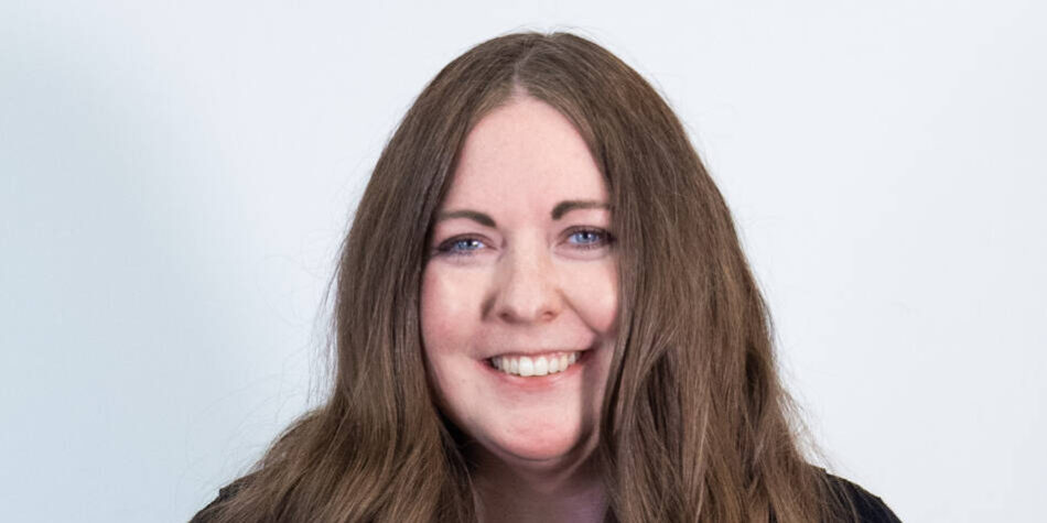 Woman with tailbone length brown hair and black cardigan