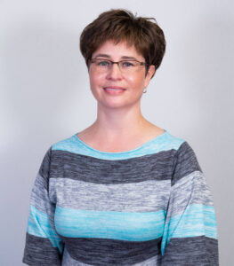Studio shot of woman with pixie cut, brown hair, and striped long sleeve