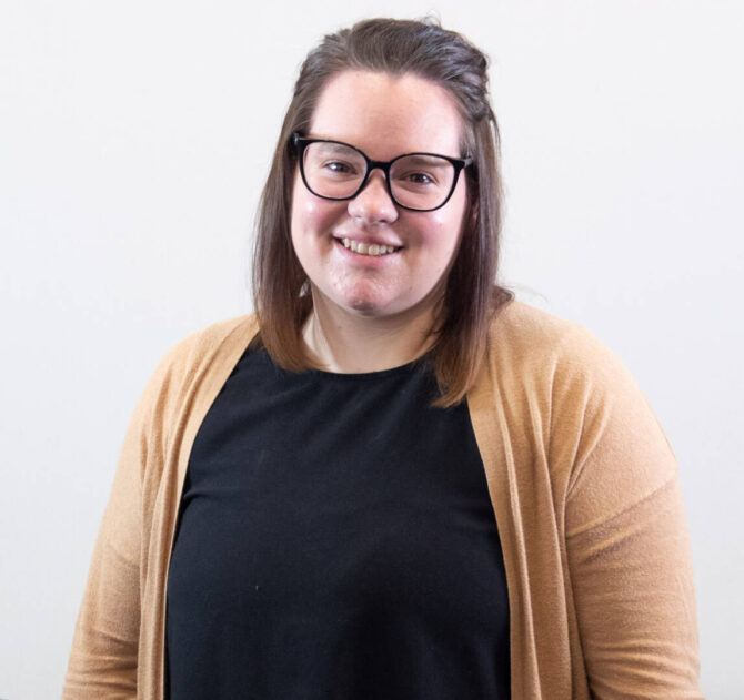 Headshot of woman with straight brown shoulder length hair and glasses