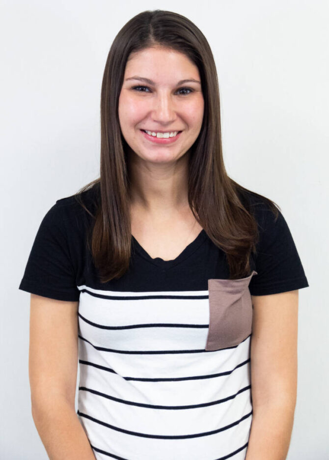 Torso-up shot of woman with dark brown straight hair and striped t-shirt, smiling at camera