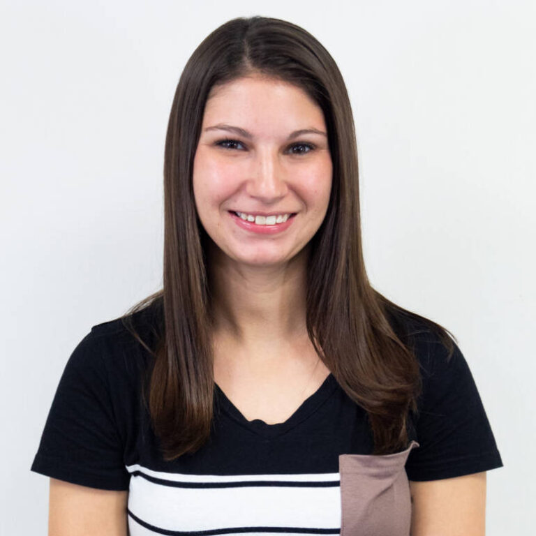 Torso-up shot of woman with dark brown straight hair and striped t-shirt, smiling at camera