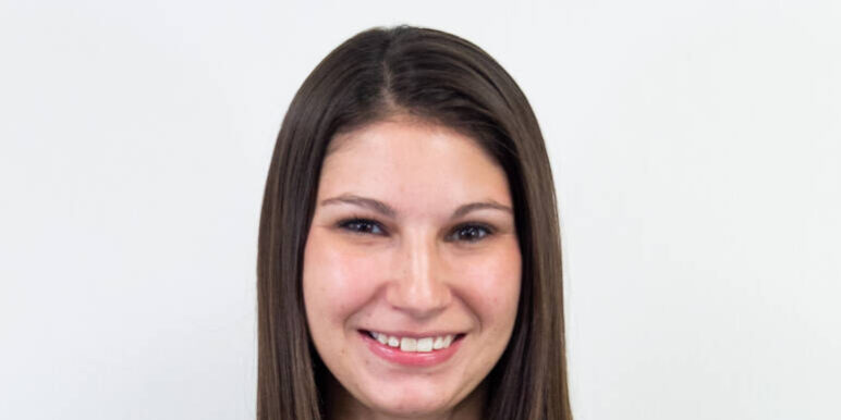 Torso-up shot of woman with dark brown straight hair and striped t-shirt, smiling at camera