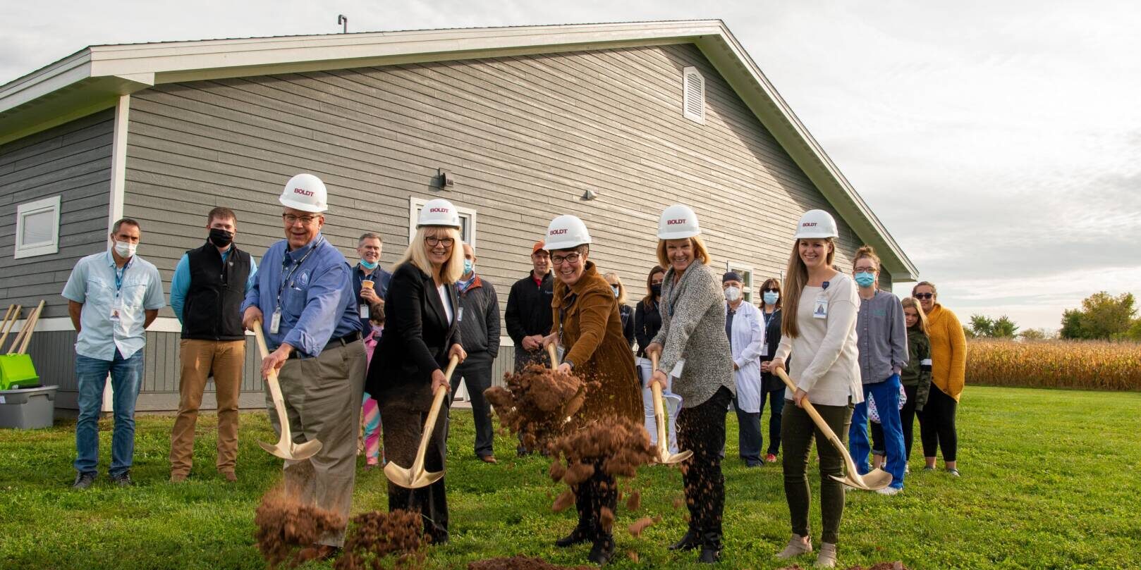 DSC_3122 Staff members outside of Turtle Lake clinic building with hard hats, shoveling dirt