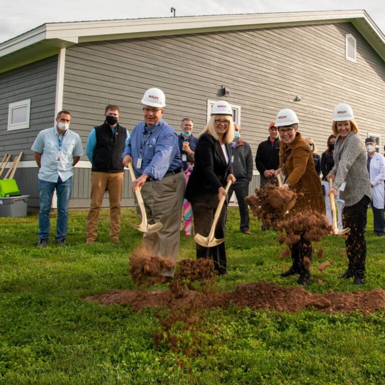 DSC_3122 Staff members outside of Turtle Lake clinic building with hard hats, shoveling dirt