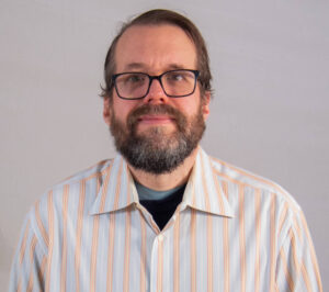 Headshot of man with striped button up and glasses
