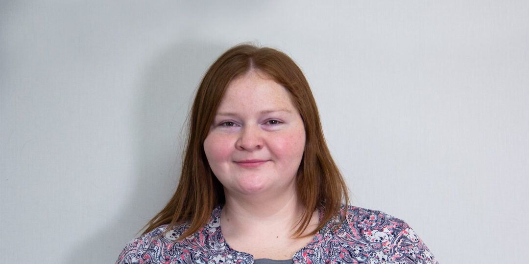 Joy-Briggs-1080×720 Headshot of woman with red hair and paisley print top