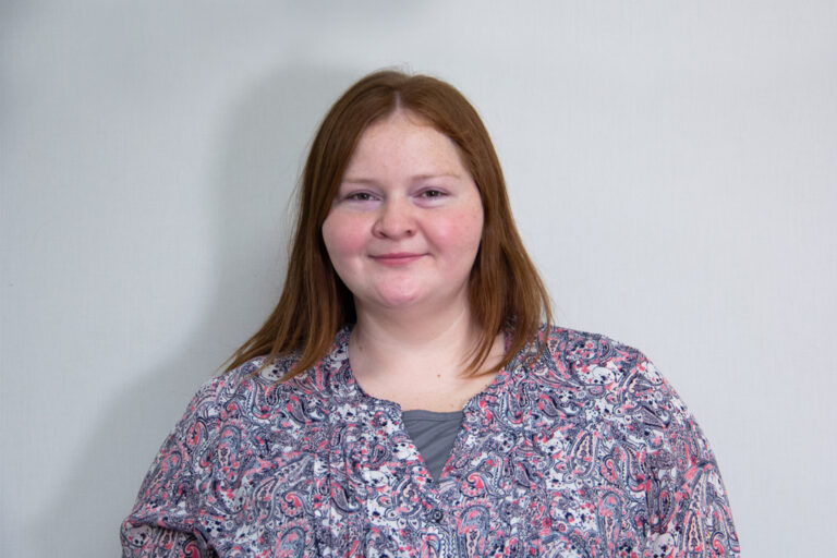 Headshot of woman with red hair and paisley print top