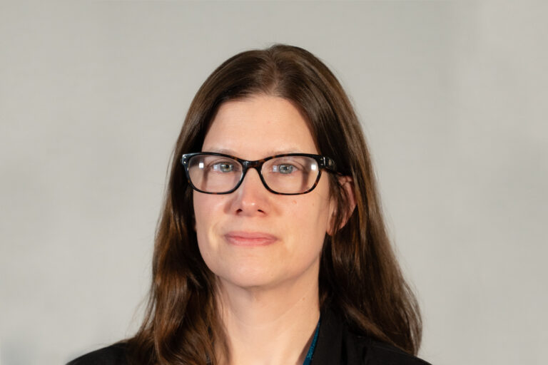 Headshot of woman with dark brown hair and glasses