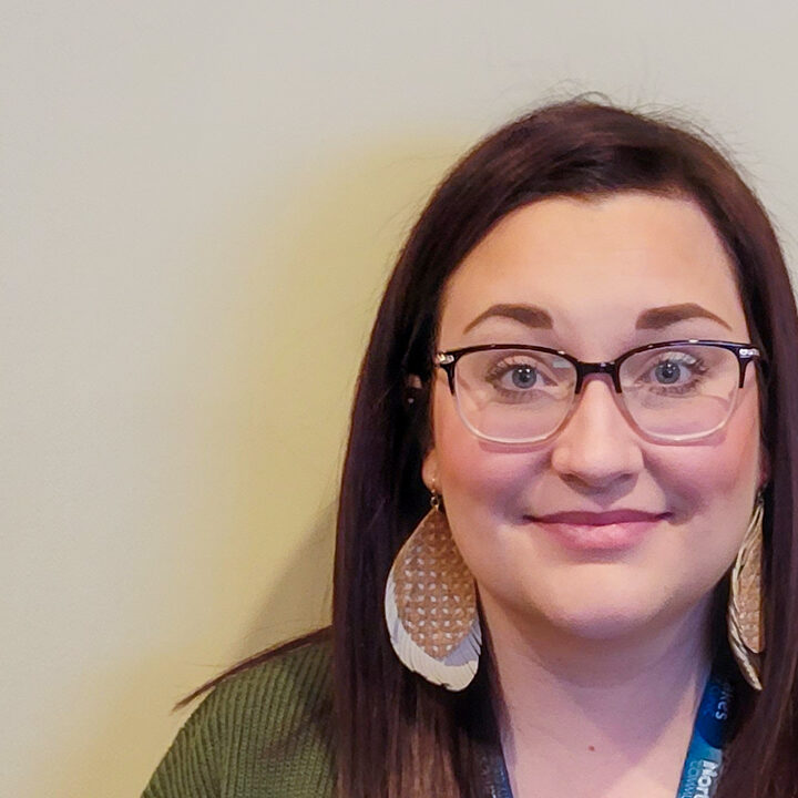 Amberae-Tauer-Blog-Photo Headshot of woman with dark brown/red hair and glasses with large earrings