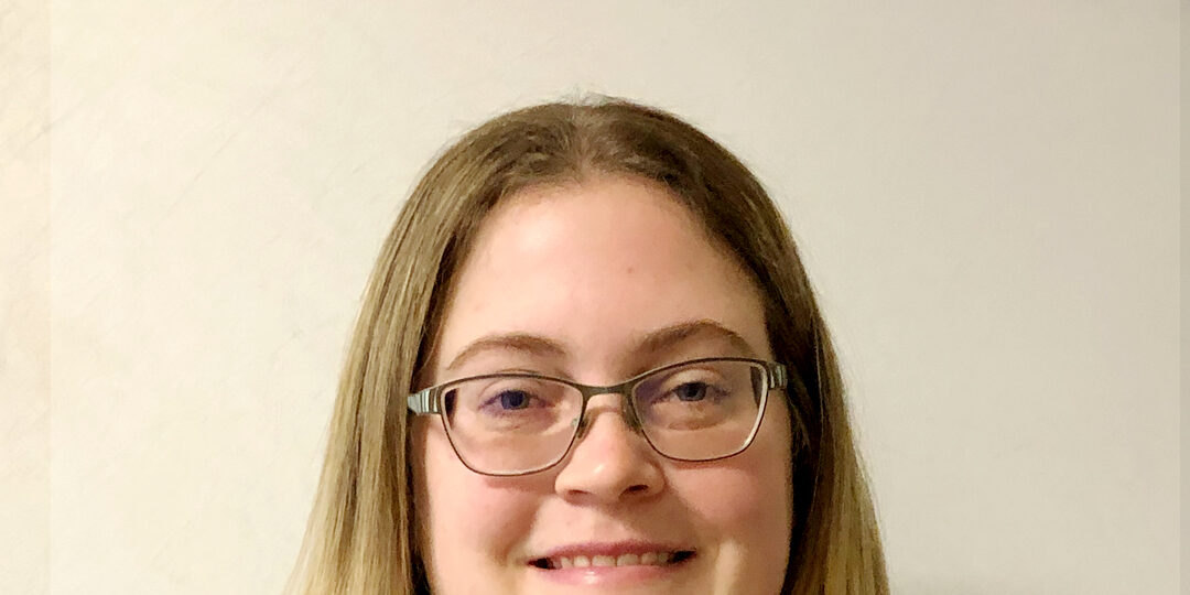 Headshot of woman with dark blonde, straight hair and glasses