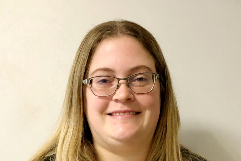 Headshot of woman with dark blonde, straight hair and glasses