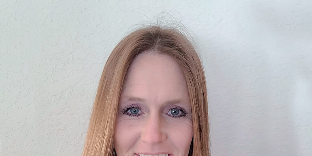 Headshot of woman with straight hair smiling at the camera