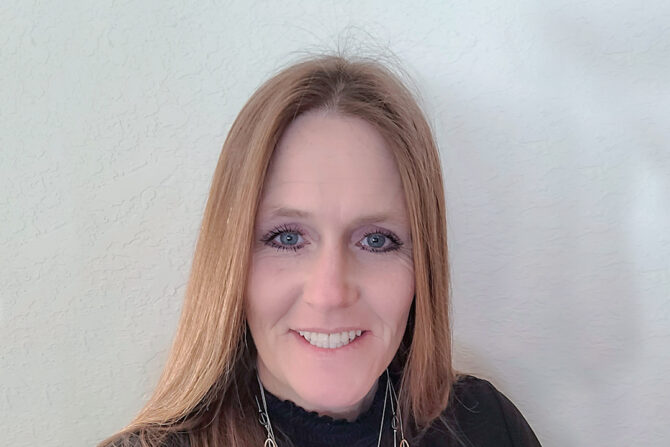 Headshot of woman with straight hair smiling at the camera