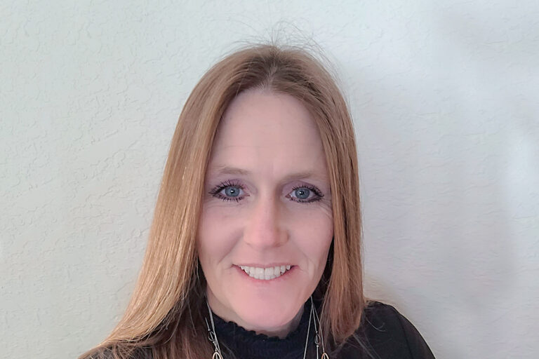 Headshot of woman with straight hair smiling at the camera