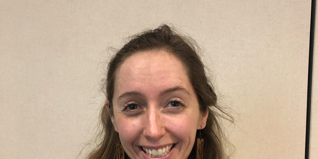 Woman with shoulder length brown hair and striped shirt smiling